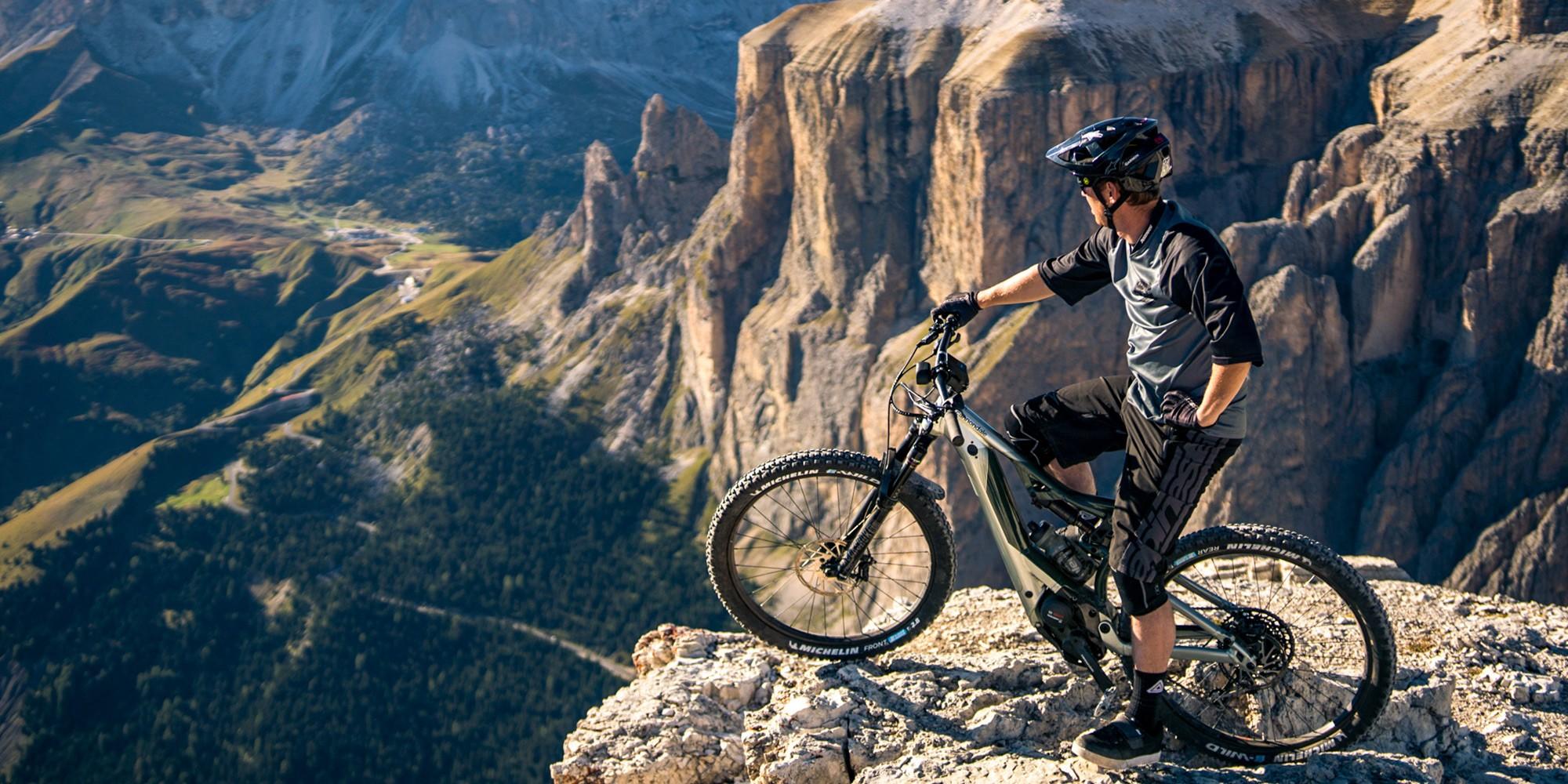 Auf dem Bild ist ein E-Mountainbike, das Cannondale Moterra NEO, abgebildet, das auf einem Aussichtspunkt steht.