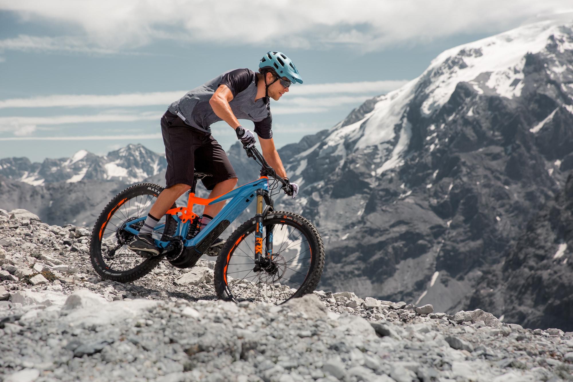 Ein Radfahrer auf einem modernen E-Mountainbike meistert steiniges Gelände in den Alpen. Ideal für Off-Road-Enthusi