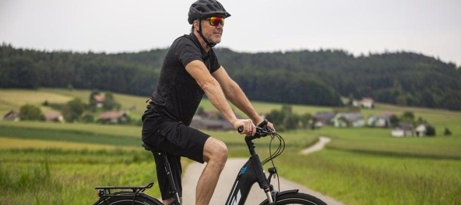 Mann auf KTM E-Bike auf ländlicher Straße mit Helm