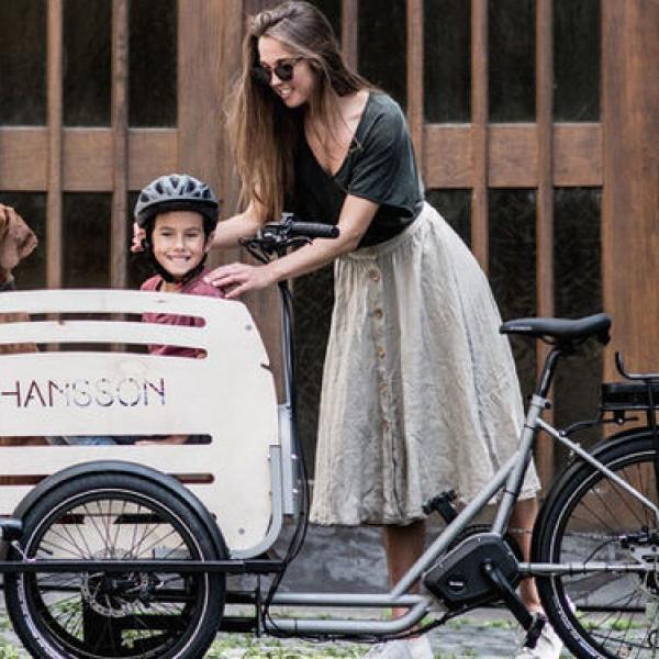 Frau steht neben dem Johansson Lastenrad, in der Transportbox Kind und Hund