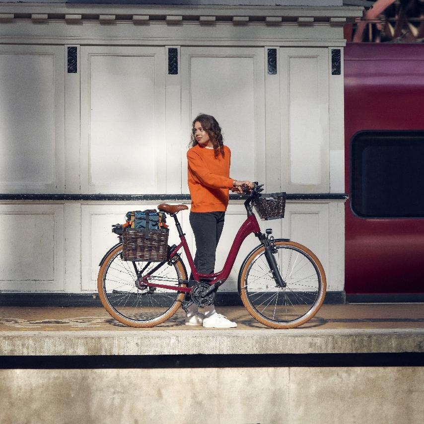 Eine Frau steht am Bahnsteig mit dem Riese & Müller Swing e-Bike