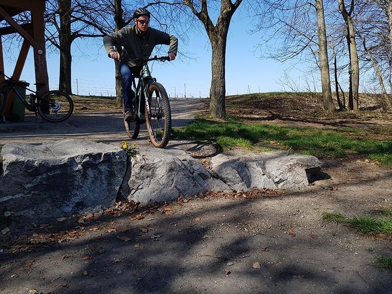 Auf dem Bild fährt ein Mann mit seinem e-Bike durch den Wald. Er springt einen Hügel hinunter.