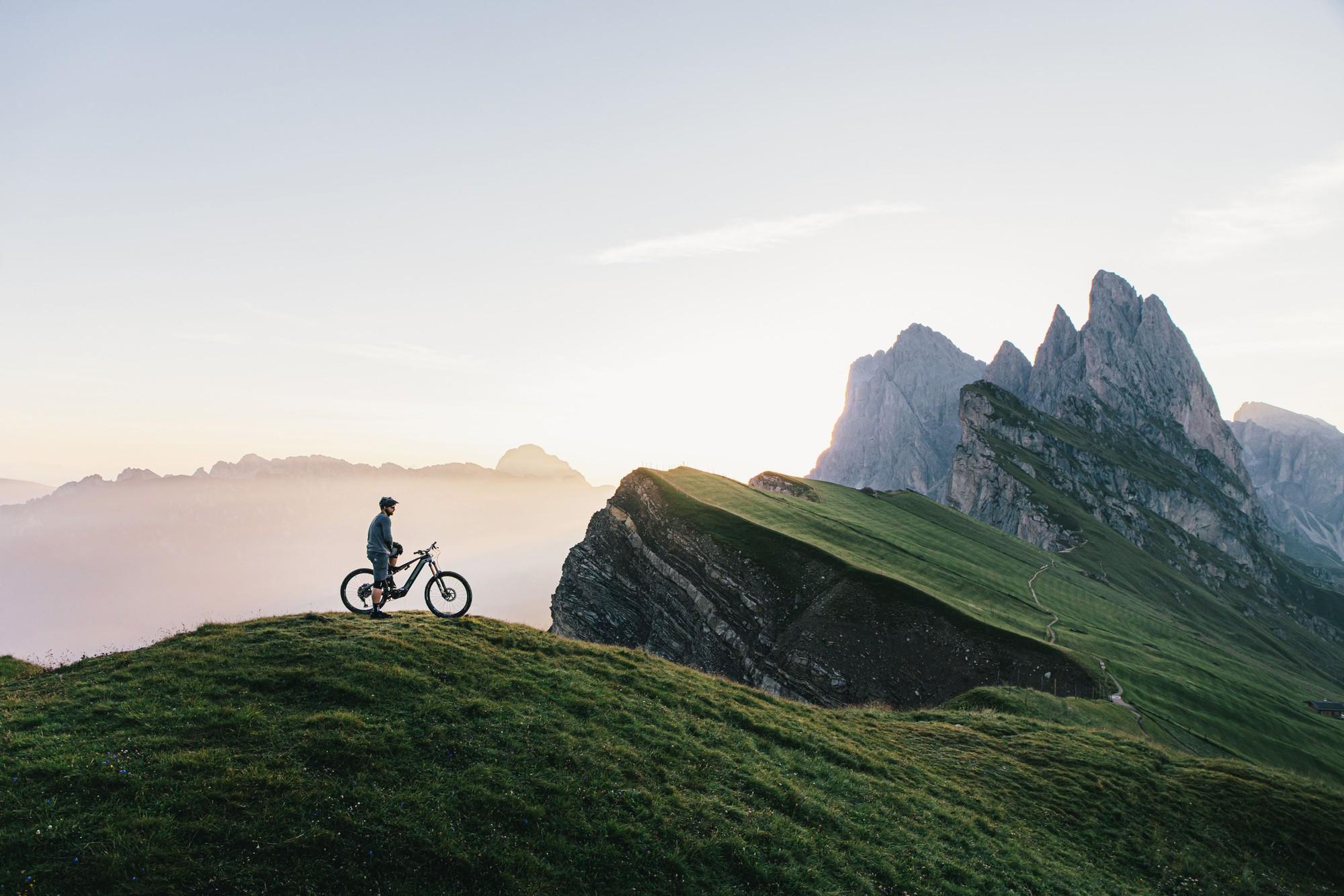 Das Bild zeigt einen Radfahrer auf einem E-Bike, der die Berglandschaft des Erzbergs im Hintergrund betrachtet.