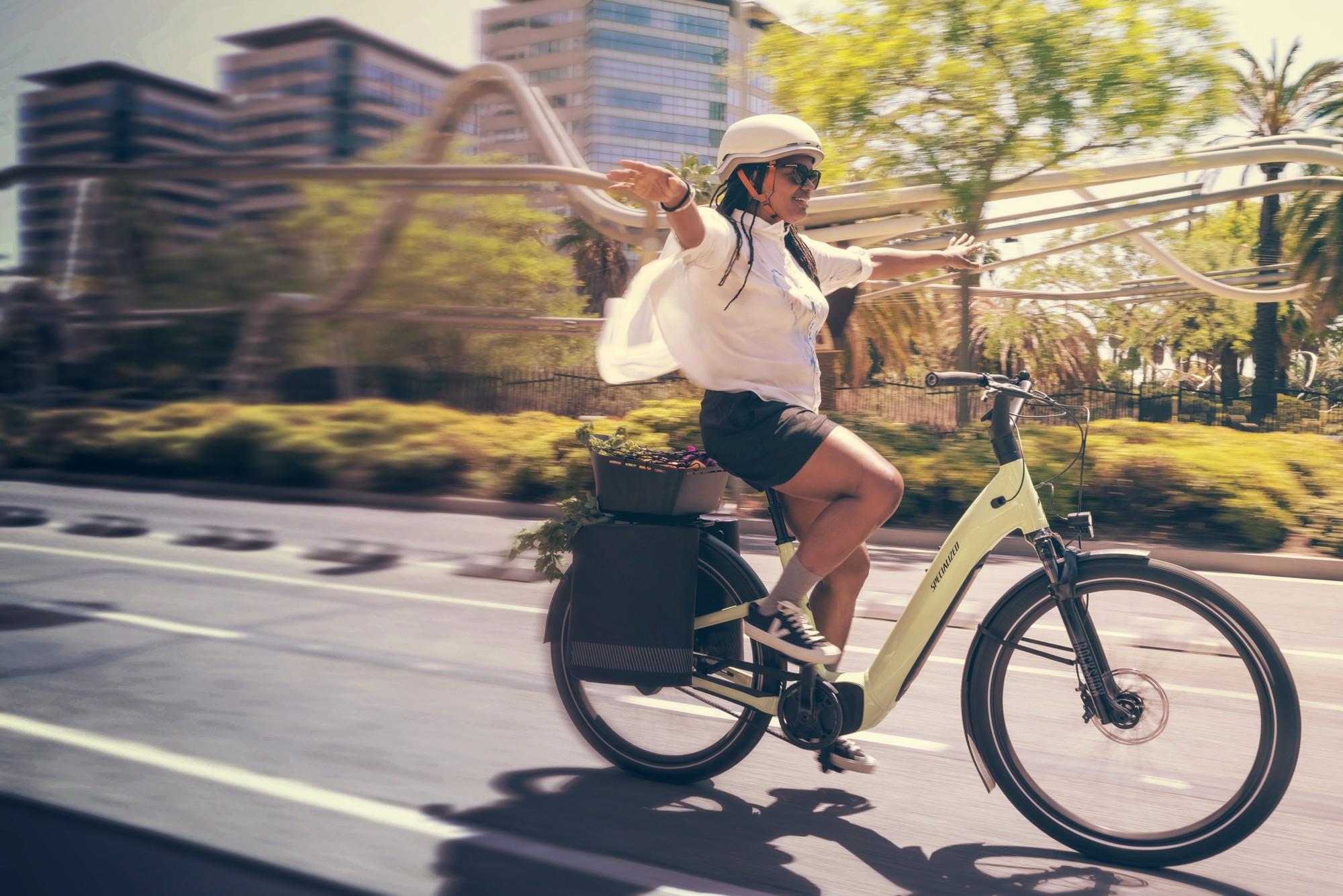 Eine Frau fährt freihändig auf dem Specialized Turbo e-Bike die Straße entlang