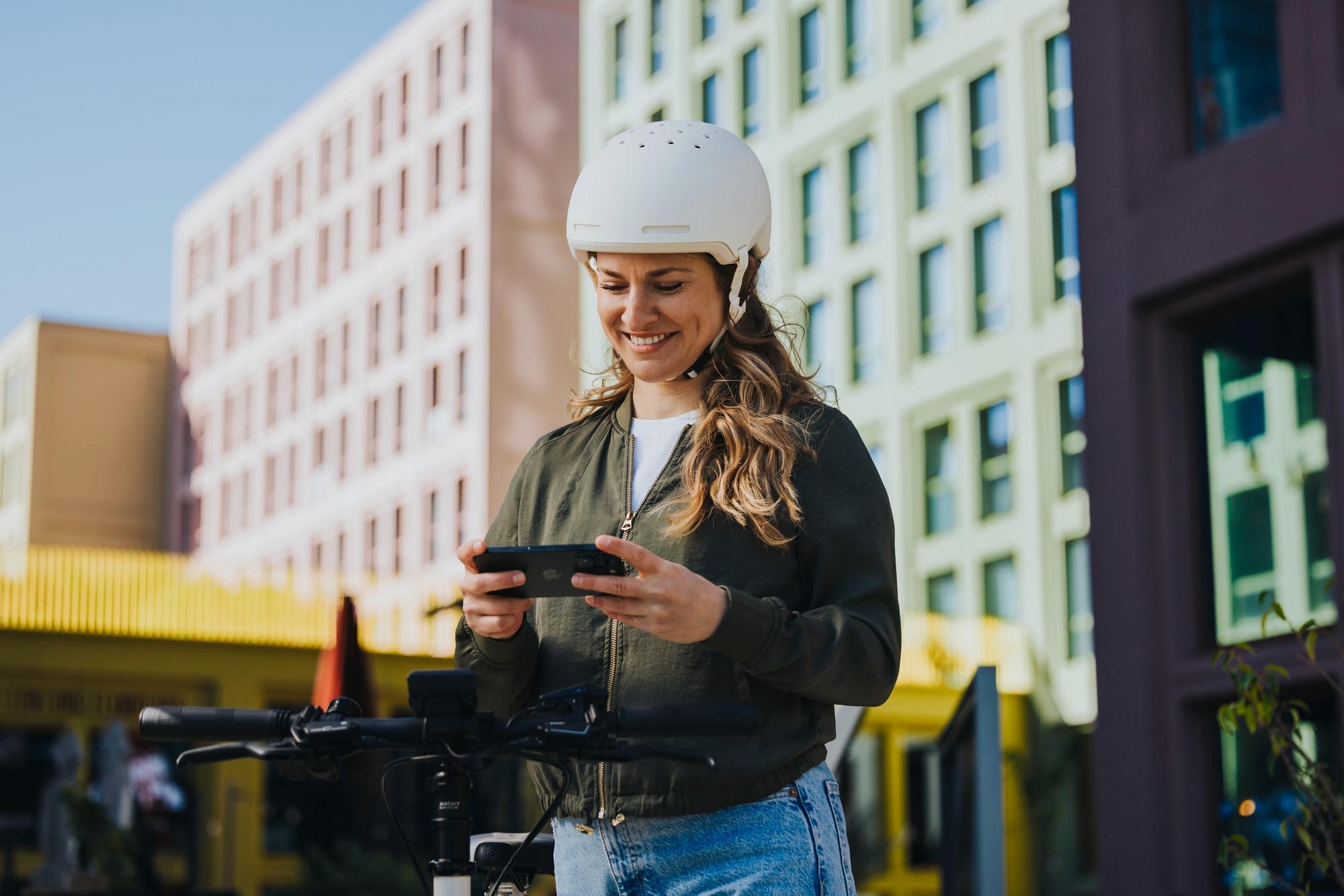 Frau steht mit Handy am e-Bike