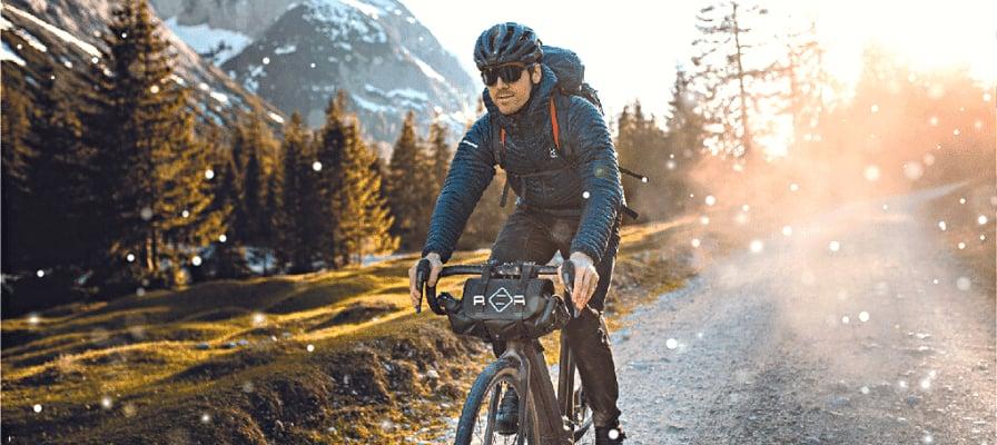 Mann auf E-Bike im Winterwald mit Sonnenuntergang