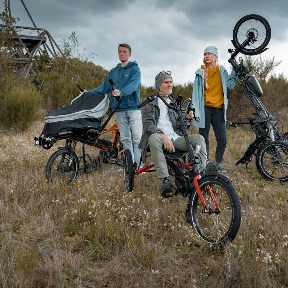 Drei Personen stehen auf einer Wiese mit verschiedenen hase bikes Modellen
