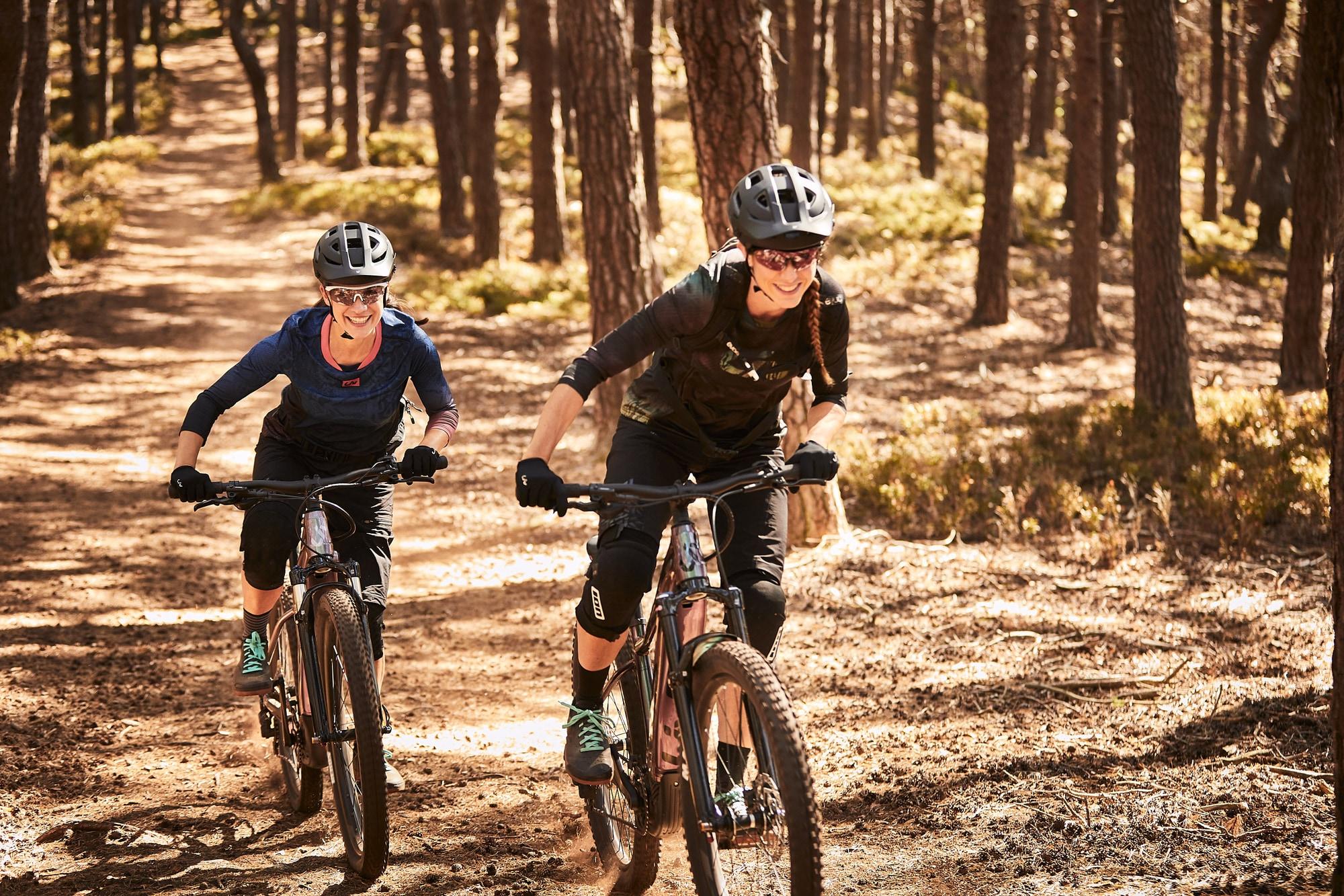 Zwei Personen genießen eine aufregende Fahrt auf E-Bikes im sonnigen Wald. Perfekt für Outdoor-Abenteuer und sportl