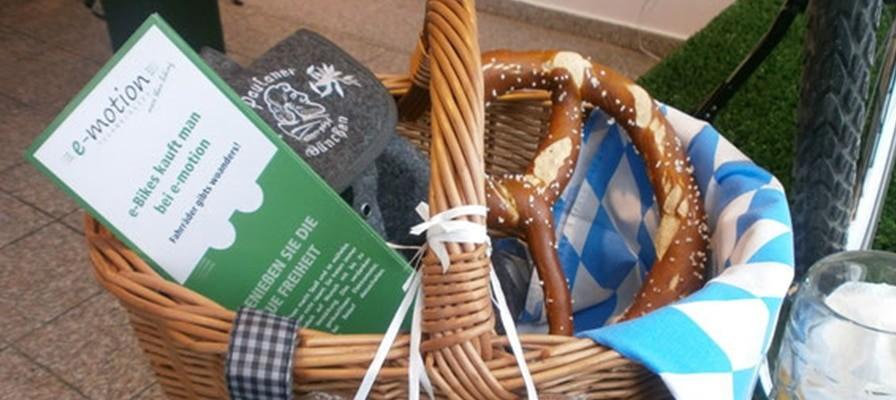 Picknickkorb am e-Bike mit Brezeln, Snacks, Decke und e-motion Prospekt.