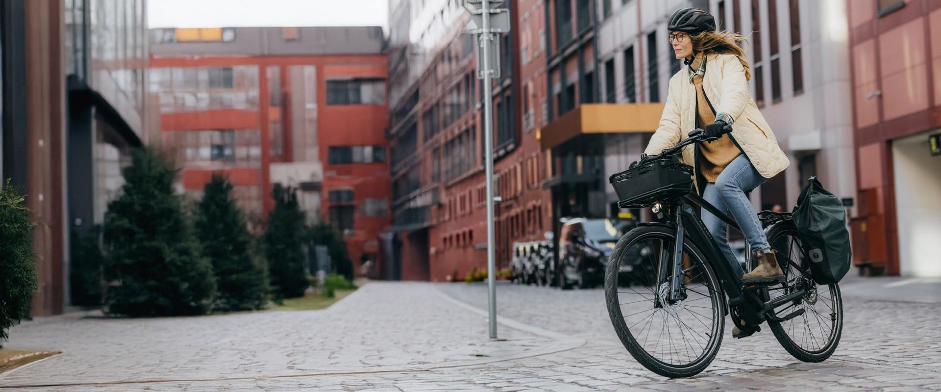 Eine Frau sitzt auf einem e-Bike im Hintergrund eine urbane Kulisse
