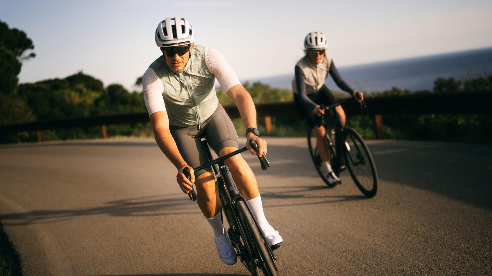 Zwei Radfahrer auf kurviger Küstenstraße, vorne ein e-Bike mit TQ HPR40 Antrieb, beide in sportlicher Kleidung.