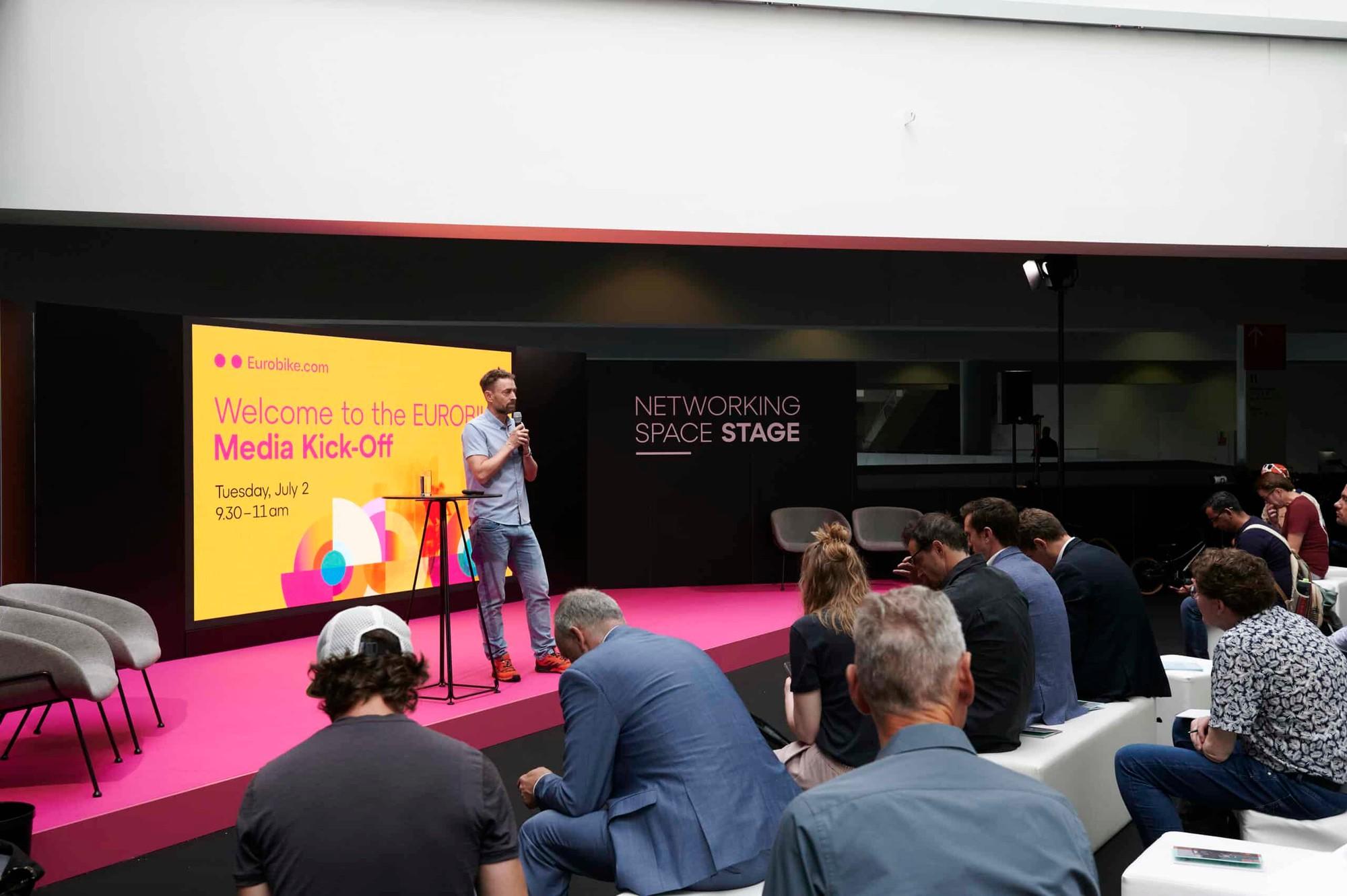 Mann steht auf der Elektrorad Bühne auf der Messe in Essen und hält einen Vortrag.