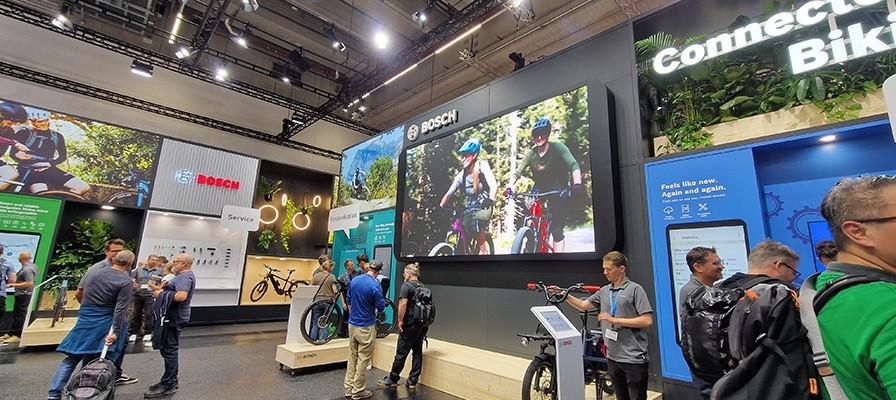 Eurobike 2024 mit Bosch-Stand, e-Bikes, Zubehör und Besuchern vor großen Bildschirmen.