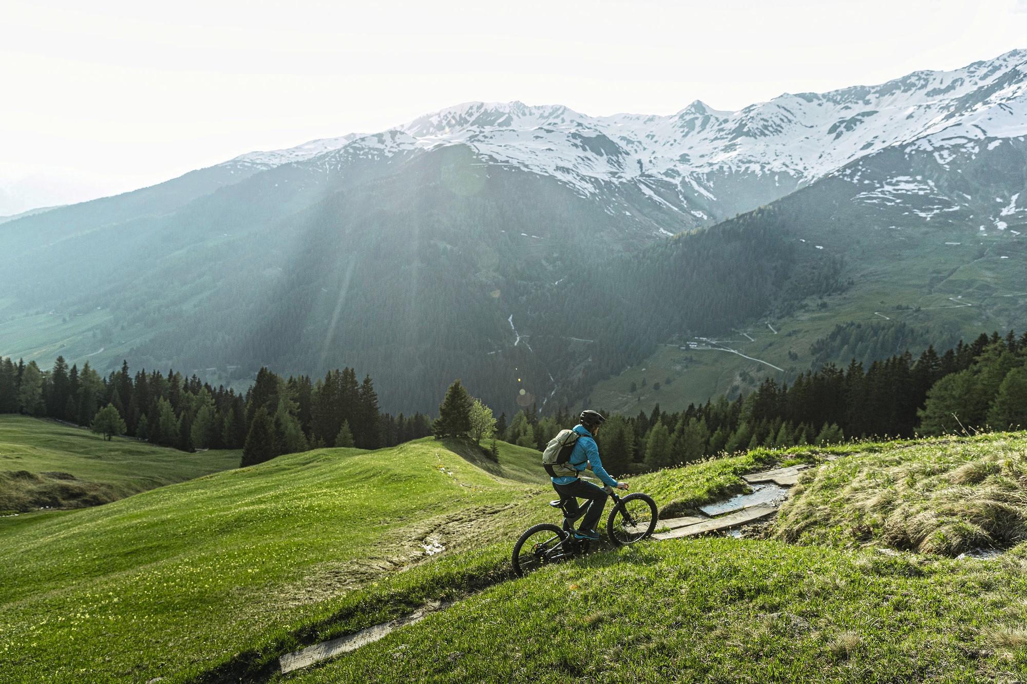 Das Bild zeigt einen Radfahrer, der auf einem Riese & Müller Superdelite Mountain E-Bike ein malerisches alpines Ge