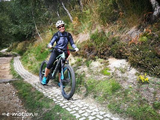 Frau fährt E-Mountainbike auf einem Naturpfad
