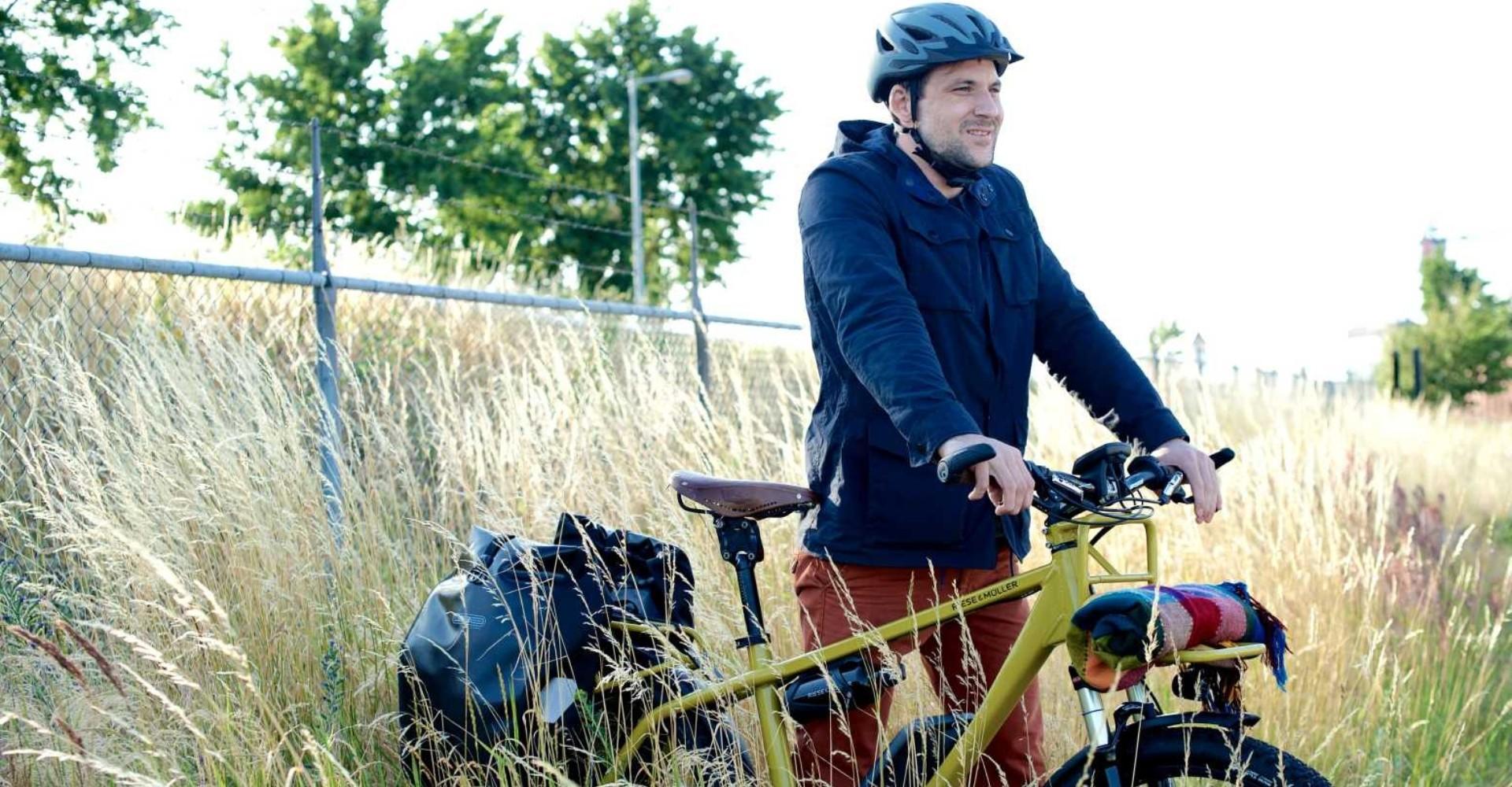 Das Riese & Müller Charger e-Bike wird von einem Mann durch die Natur geschoben.