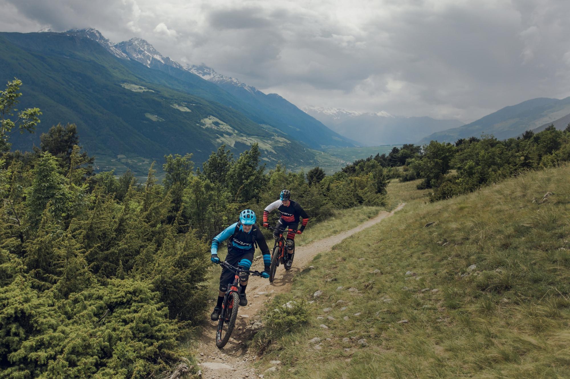 Zwei Radfahrer auf leistungsstarken E-Bikes erkunden einen malerischen Bergpfad. Erleben Sie Freiheit und Entdeckun