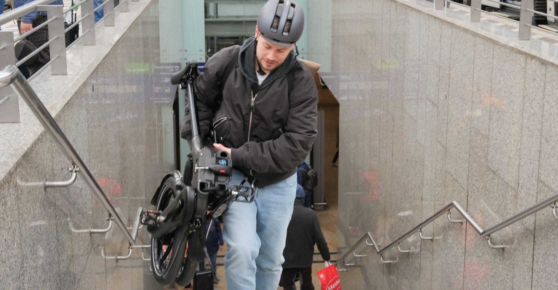 Ein Mann trägt ein Brompton e-Bike Faltrad in Gießen die Treppe hoch, super praktisch in der Stadt.