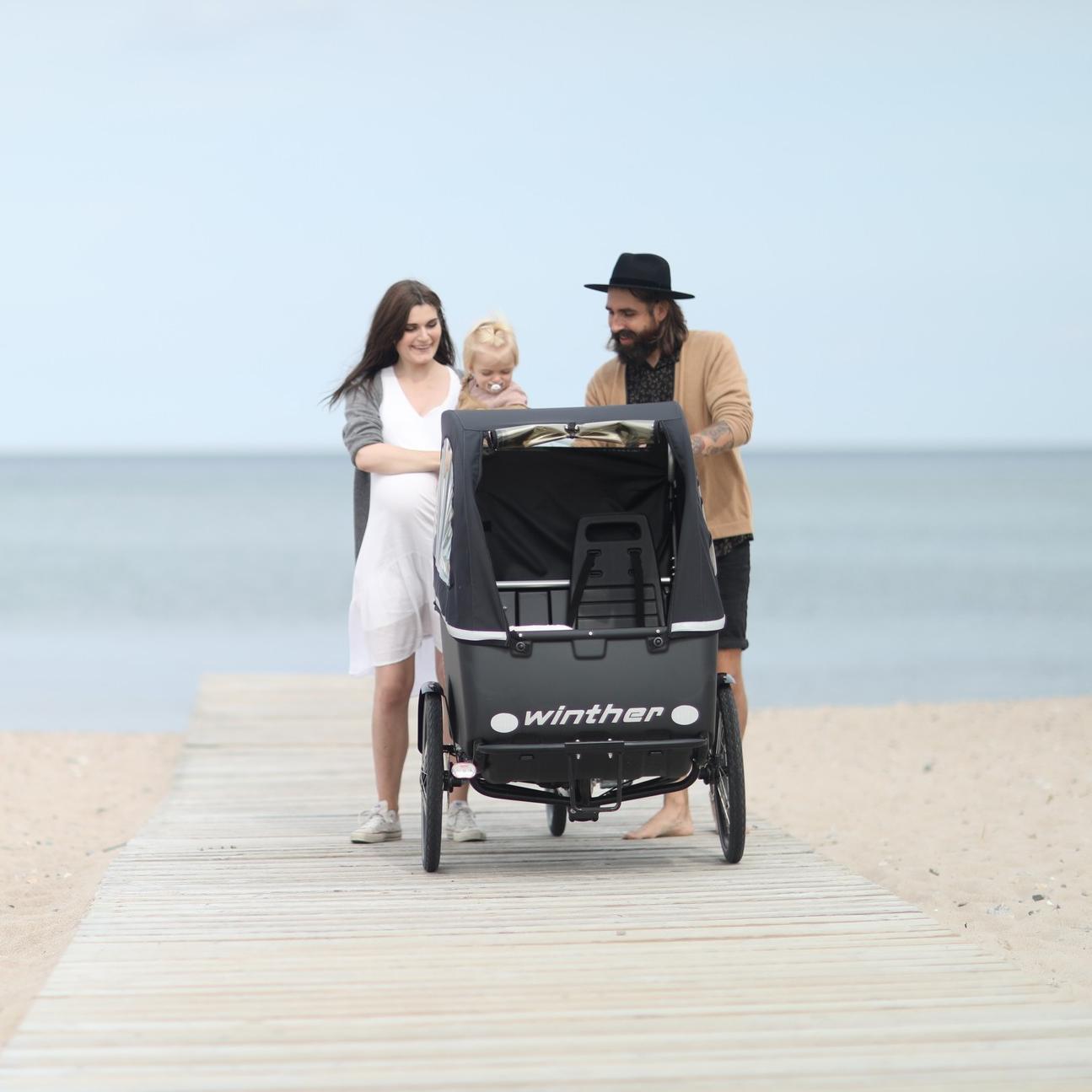 Eine Familie spaziert am Meer entlang mit dem Winther Kangaroo Lastenrad
