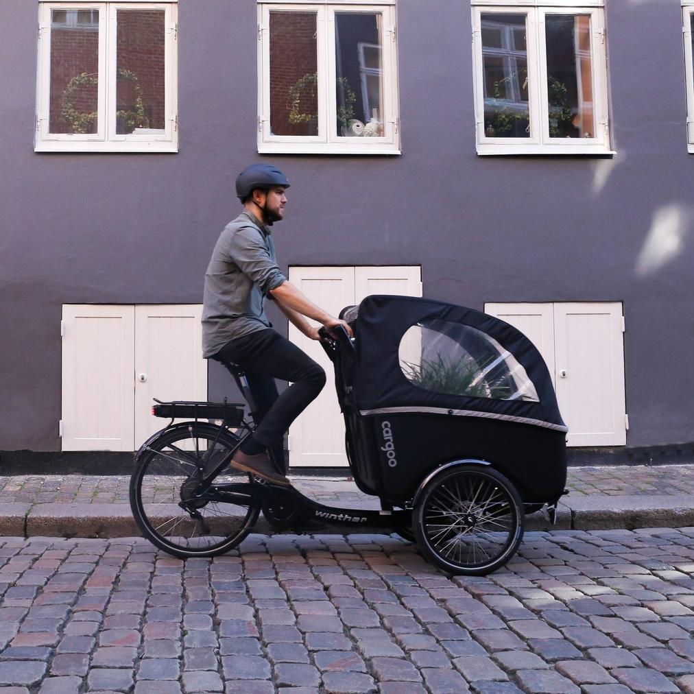 Ein Mann fährt auf dem Winther Cargoo Lastenrad durch die Stadt