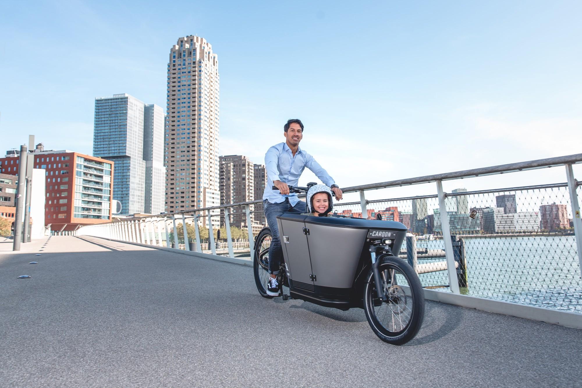 Ein Vater bringt sein Kind auf einem Carqon e-Lastenrad zum Kindergarten.