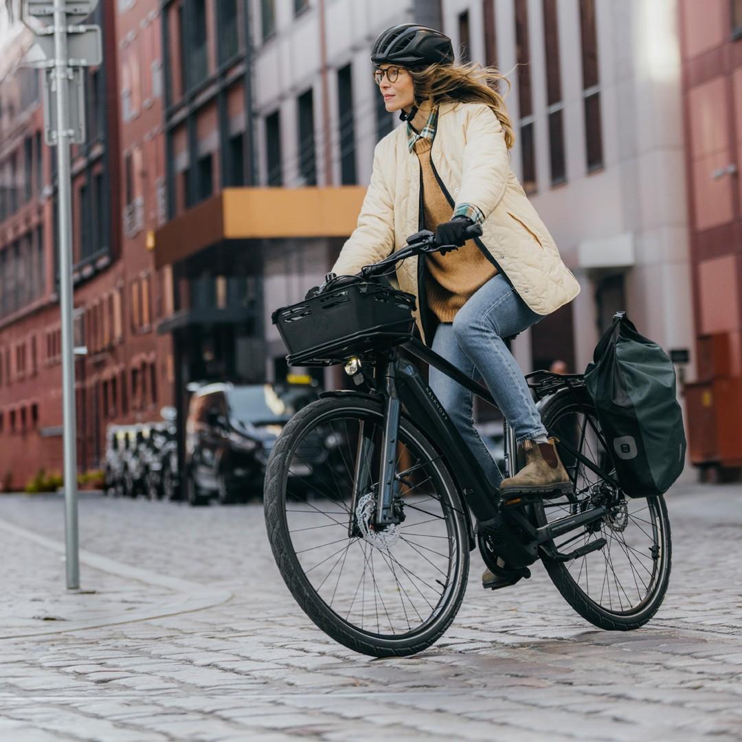 Eine Frau sitzt auf einem e-Bike im Hintergrund eine urbane Kulisse