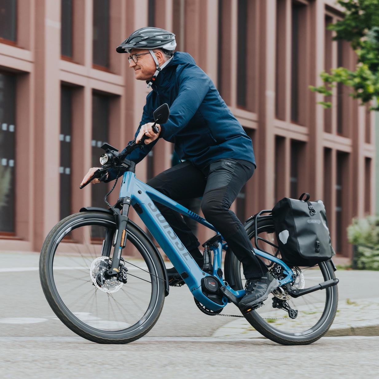 Ein Mann fährt mit seinem Speed Pedelec mit Bosch e-Bike Motor mit Geschwindigkeit durch die Stadt.