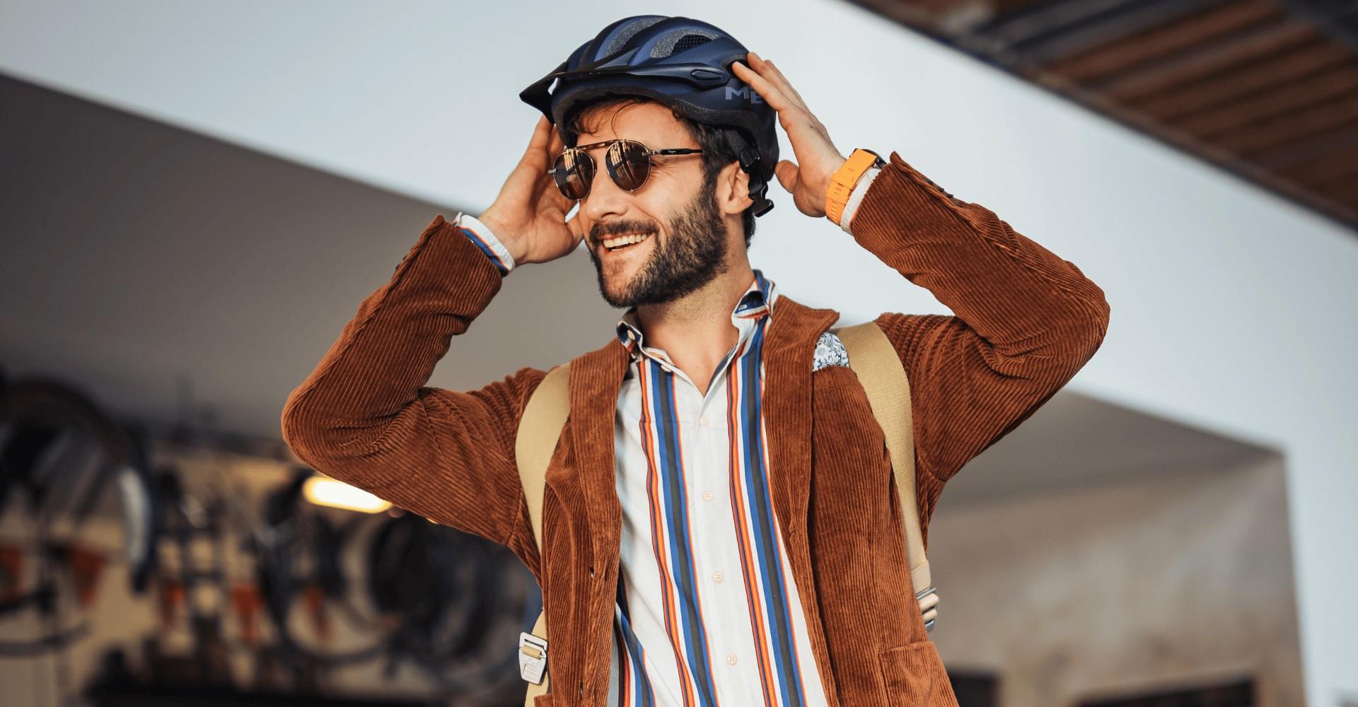 Ein Mann im Sakko setzt sich einen Fahrradhelm auf
