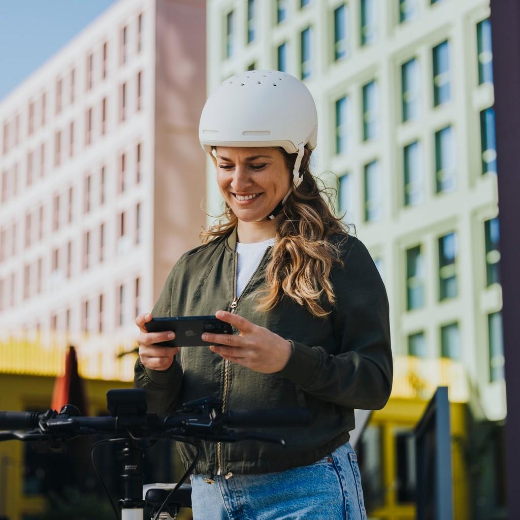 Frau steht mit Handy am e-Bike