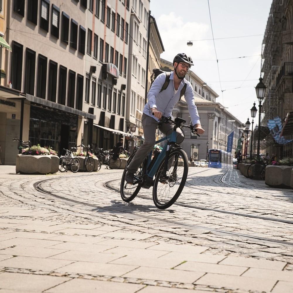 Ein Mann fährt mit Bosch e-Bike auf den Schienen im urbanen Umfeld