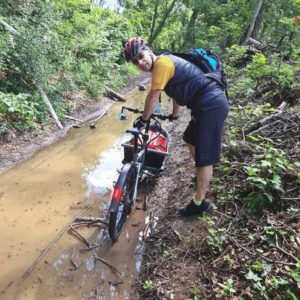 Person mit E-Bike auf schlammigem Waldweg