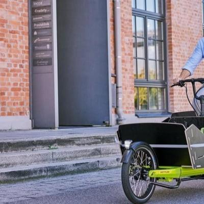 Mann fährt Cargoline FS 800 Lastenrad vor Backsteingebäude