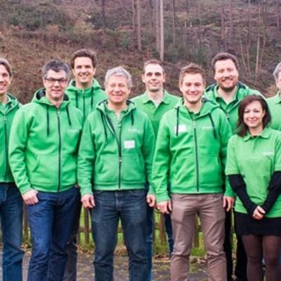 Gruppe in grünen Jacken vor Wald mit e-motion Banner