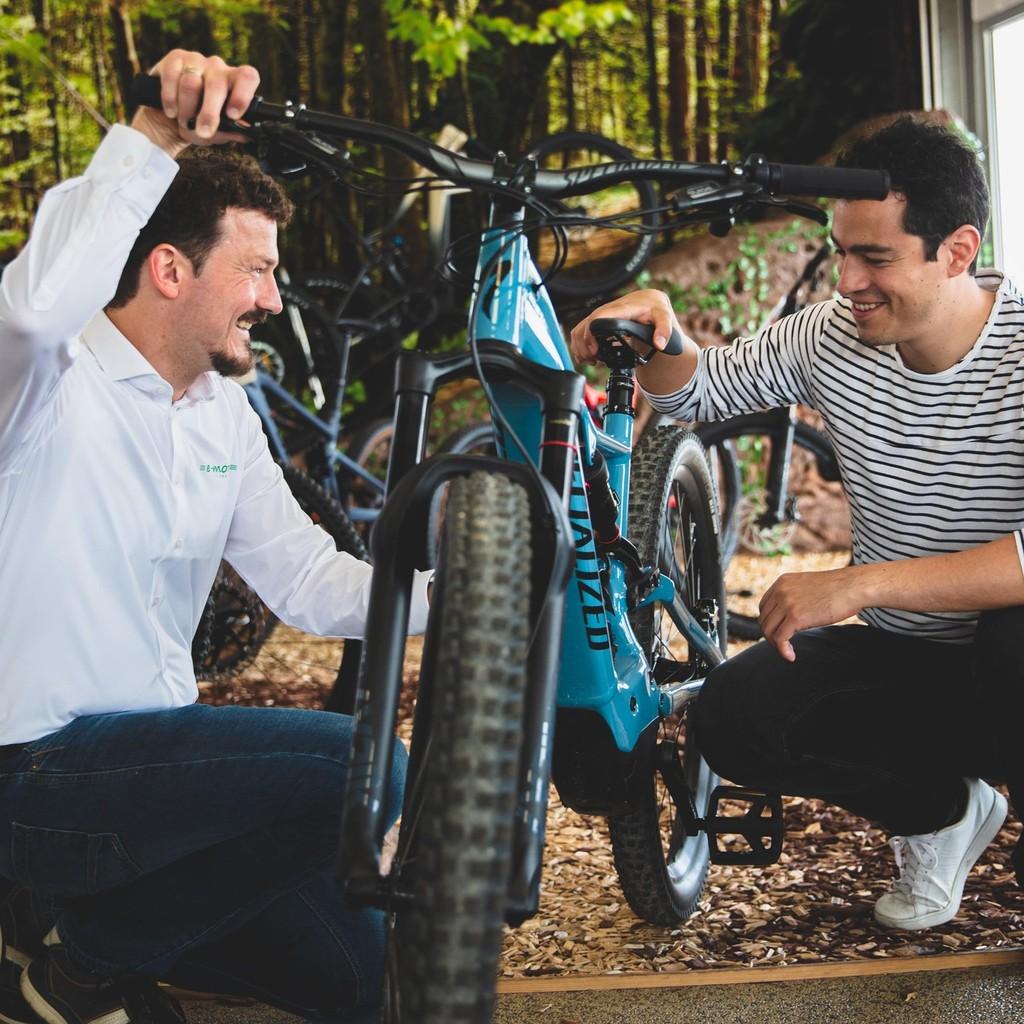 Zwei Personen sitzen vor einem e-Bike und schauen sich die Ergonomie des Bikes an