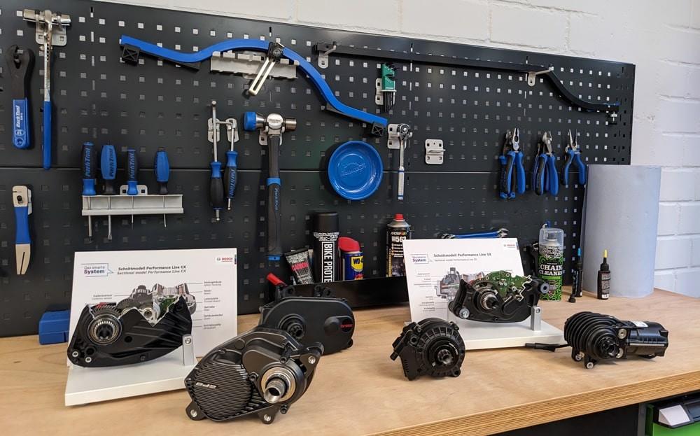 Eine Übersicht verschiedener Motoren auf einem Tisch, im Hintergrund eine Werkzeugwand