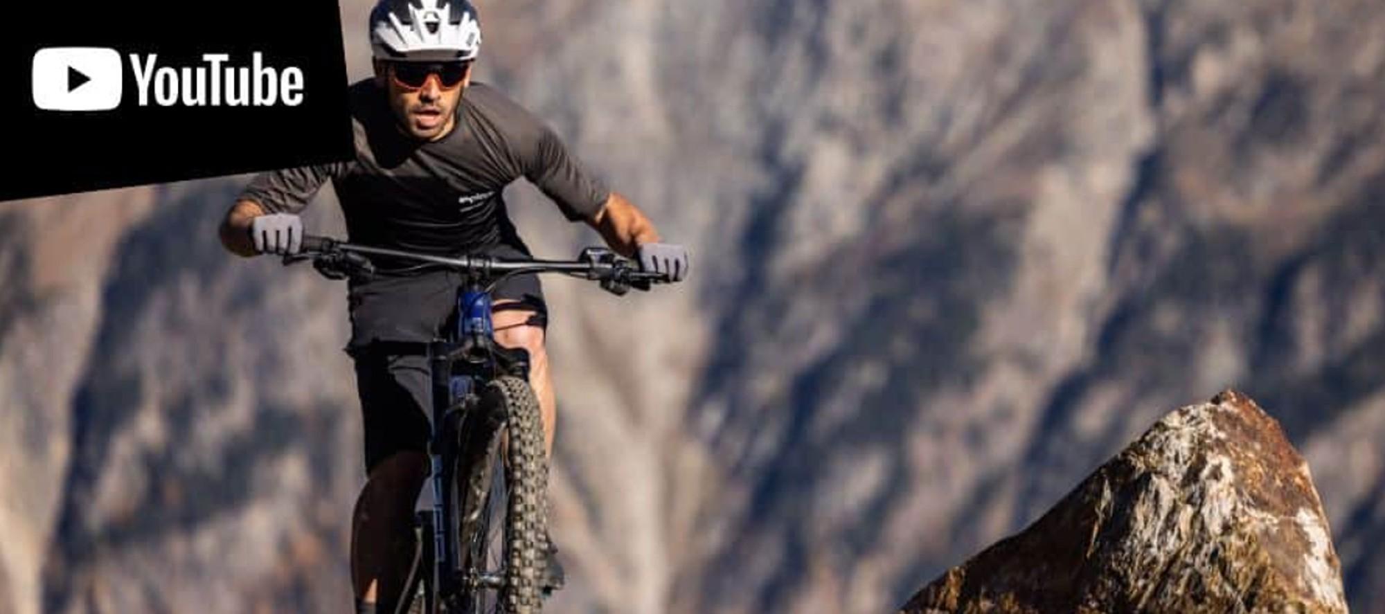 Das Bild zeigt einen Fahrer auf einem Corratec MTC E-Bike, der dynamisch über einen felsigen Untergrund fährt. Der