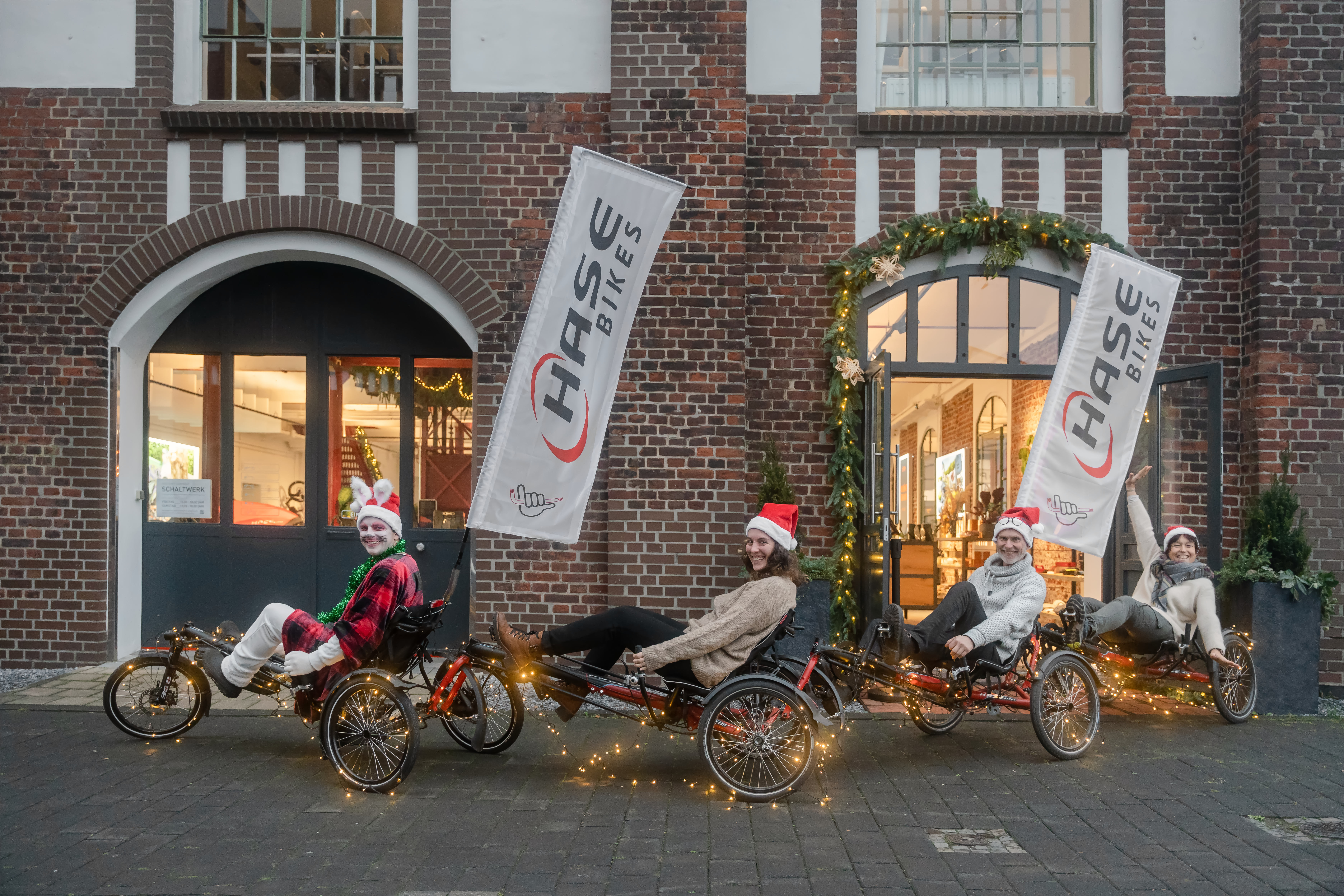 Mehrere Dreirad e-Bikes stehen vor dem weihnachtlichen Store mit Hase Bike Banner.