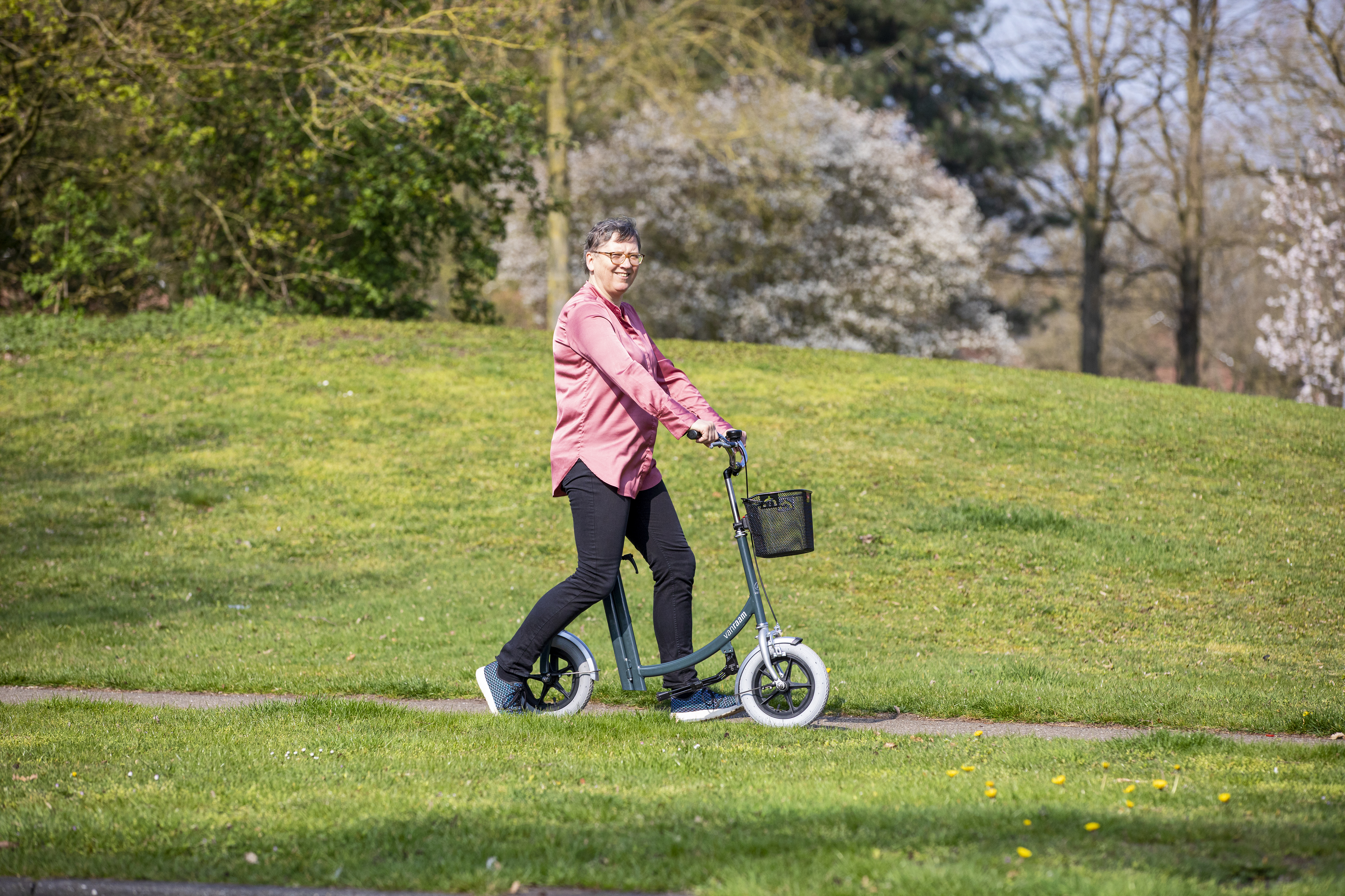 Eine Frau nutzt die Van Raam Laufhilfe um einen entspannten Spaziergang durch den Park zu machen.