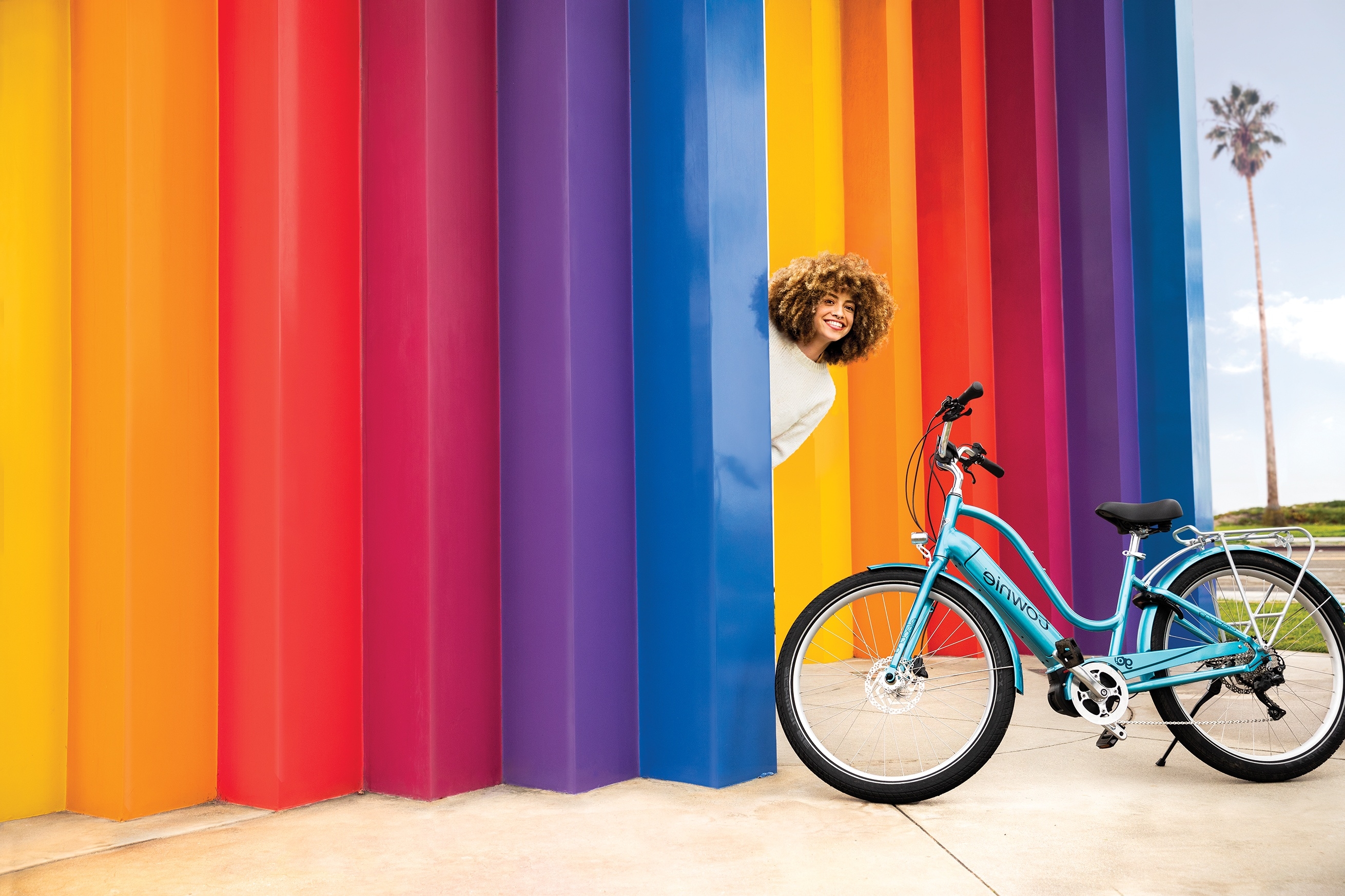 Frau hinter einer Regenbogenwand neben einem Electra Townie Go!