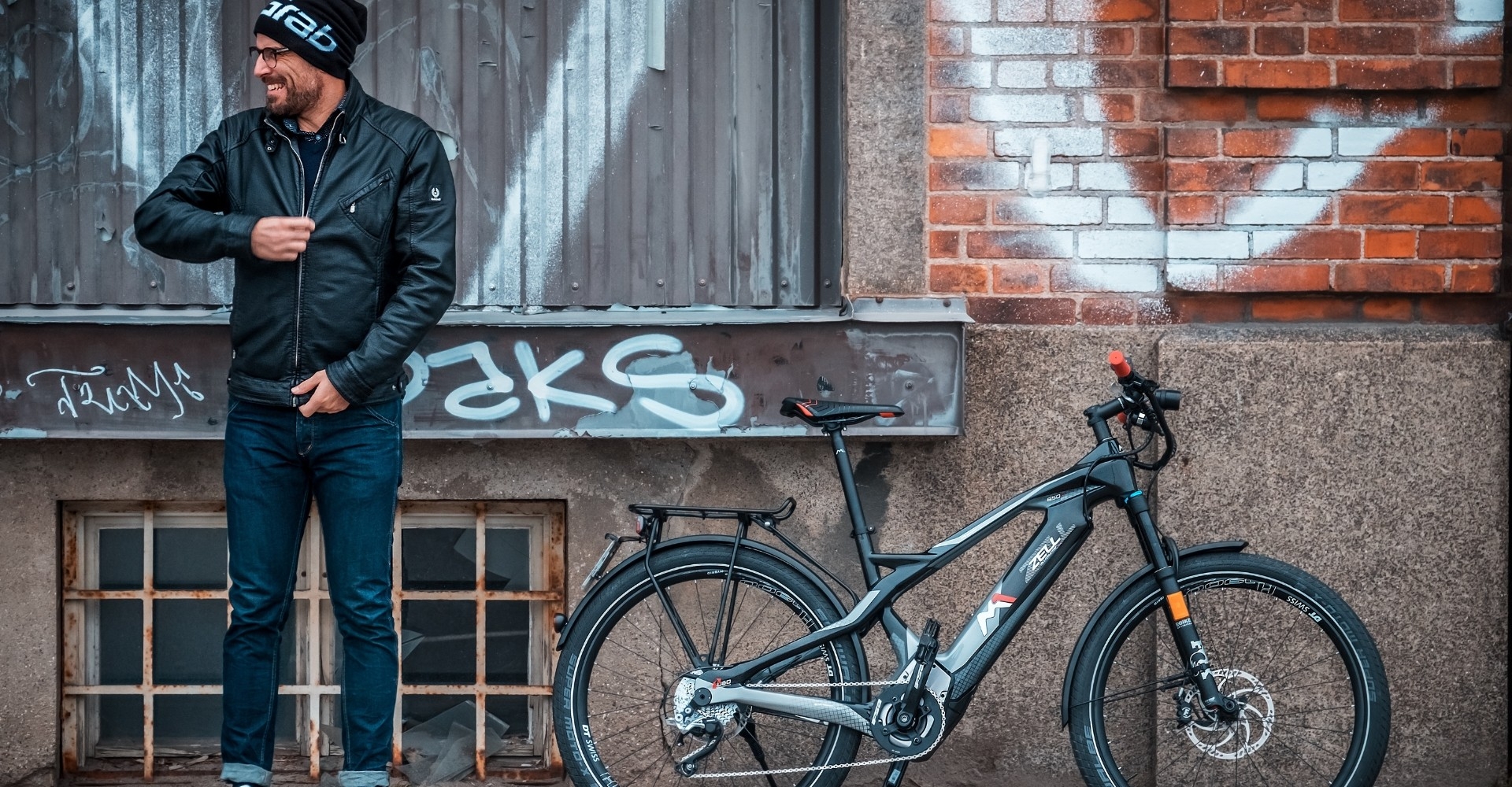 Mann mit M1 Zell e-Bike vor einer Wand