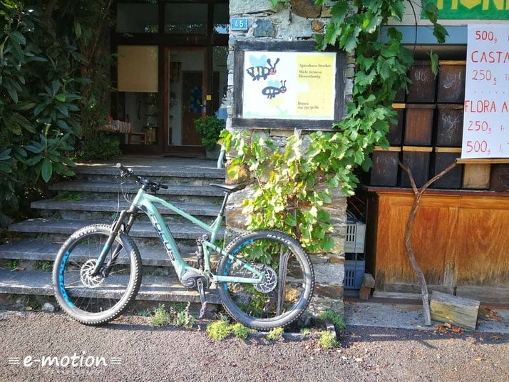 E-Mountainbike vor einem Gebäude mit Steinmauer und Pflanzen