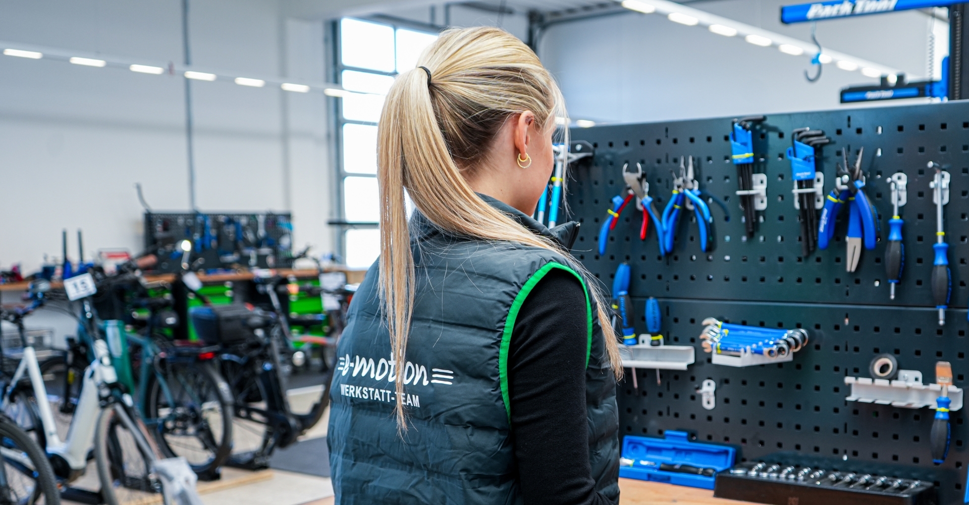 Eine Frau steht in einer e-motion e-Bike Welt Werkstatt vor einer Werkzeugwand