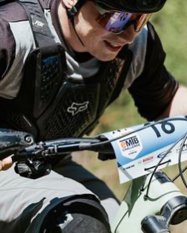 Ein E-Mountainbike-Fahrer mit Schutzkleidung nimmt an einem Rennen teil. Die Bosch-Startnummer zeigt Engagement im