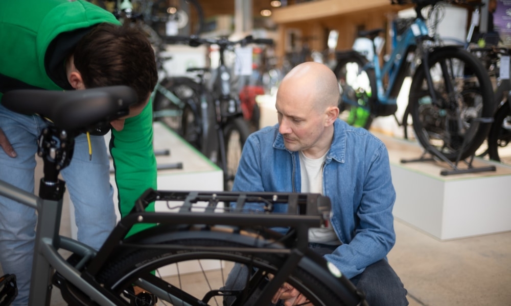 Ein e-motion Mitarbeiter untersucht ein E-Bike im Geschäft. Perfekte Beratung für E-Bike-Käufer vor Ort.