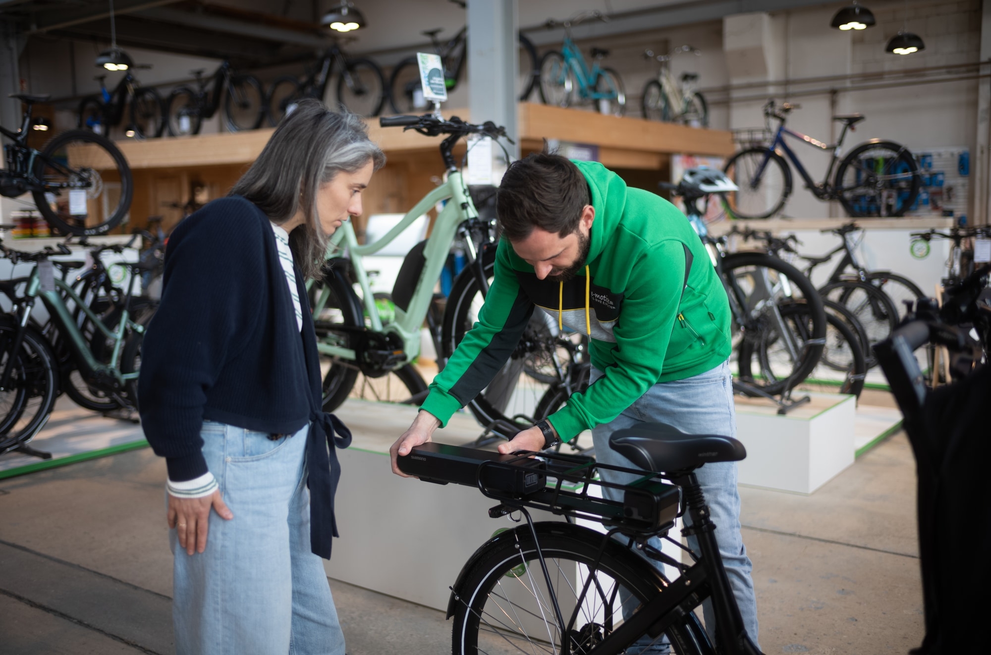 Ein Mitarbeiter der e-motion e-bike Welt in Oberhausen berät eine Kundin zum e-Bike Akku.