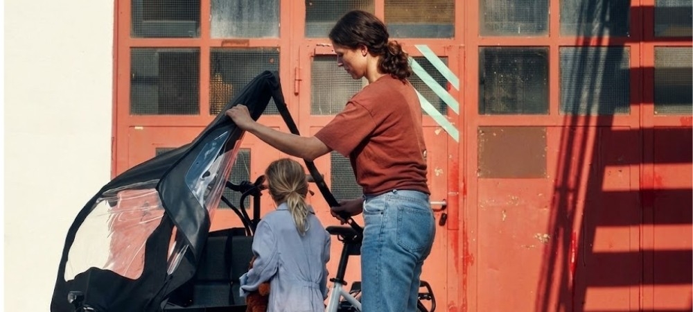 Eine Frau steht mit einer Tochter vor dem Riese und Müller Transporter Lastenrad