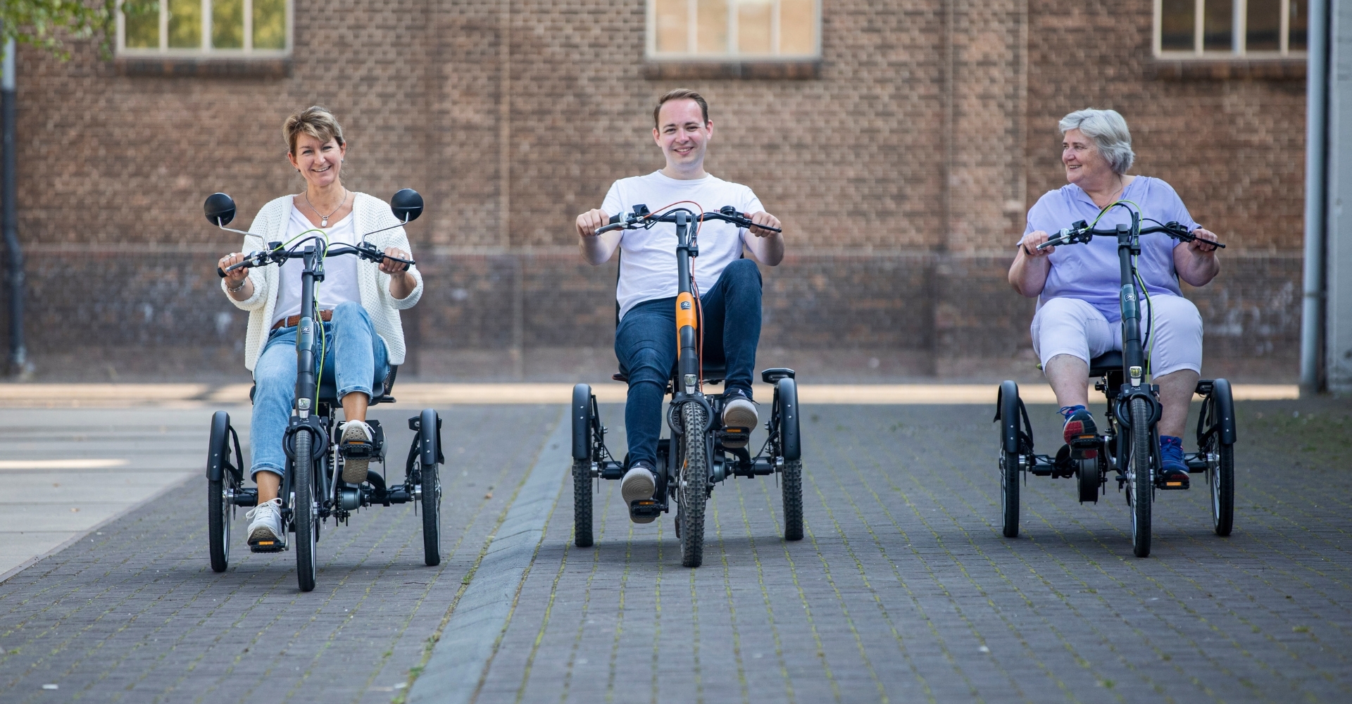 Drei Personen unterschiedlichen Alters sitzen auf Easy Rider Dreirädern von van Raam