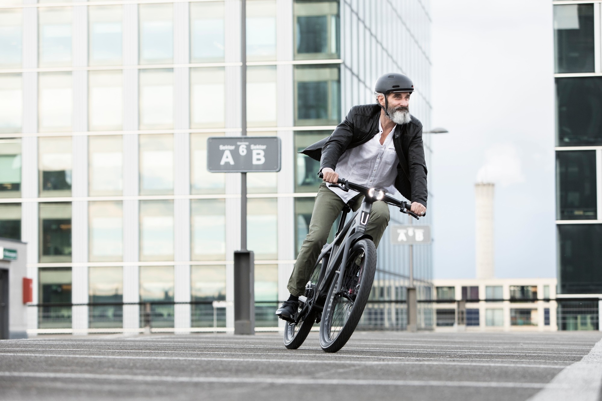 Das Bild zeigt einen Mann, der auf einem modernen E-Bike in einer urbanen Umgebung fährt.
