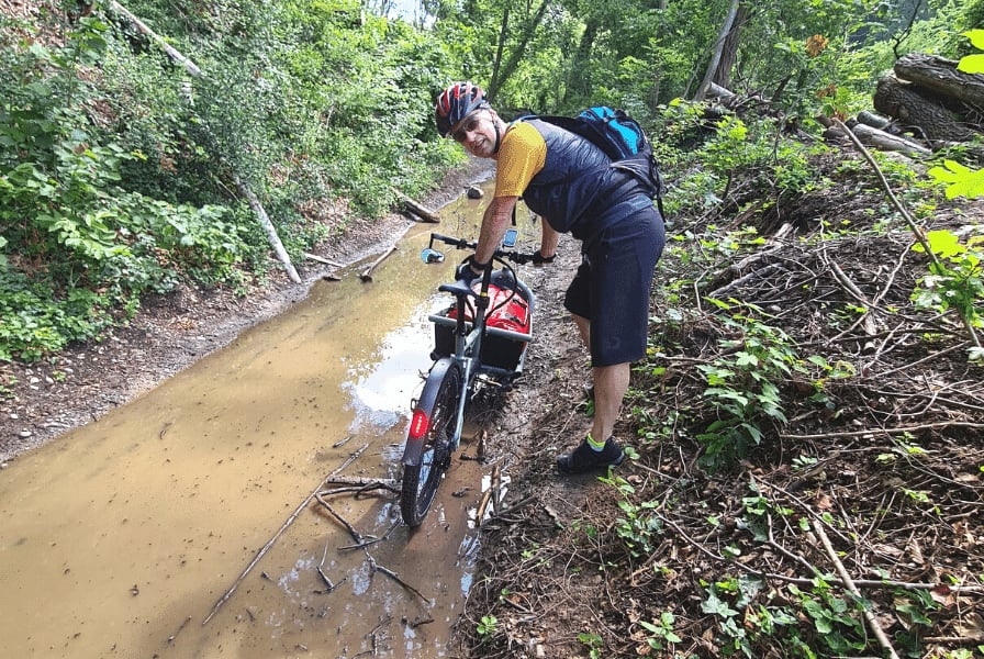 Person mit E-Bike auf schlammigem Waldweg