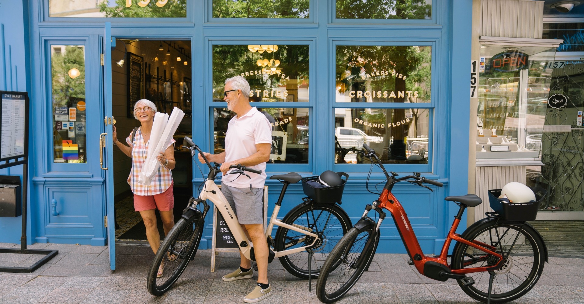 Ein älteres Ehepaar macht eine e-Bike Tour und steht gerade vor einem Geschäft.
